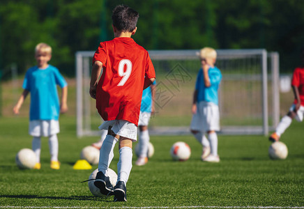 孩子们在球场上训练足球小男孩在草地上踢足球穿着运动服的孩子们图片