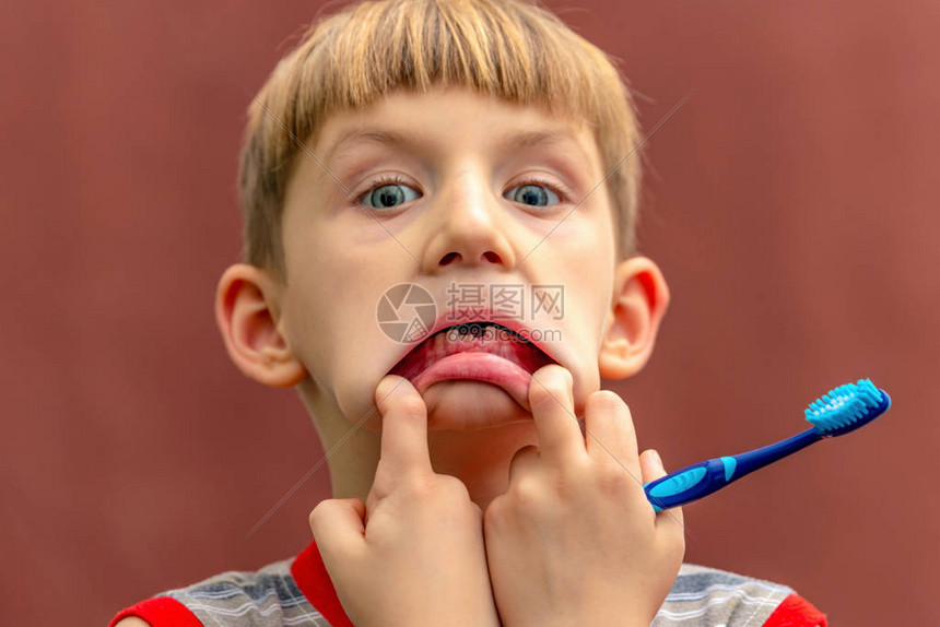一个手拿着牙刷的孩子脸上有张无牙的图片