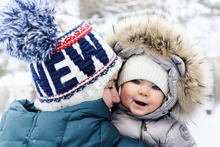 穿着冬衣微笑的妈拥抱冬天在公园的婴儿无图片