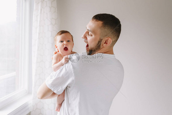 快乐的白种人父亲抱着刚出生的婴儿男大胡子男父母模仿他打呵欠的女儿子真实的生活方式坦率有趣的时刻年轻爸的图片