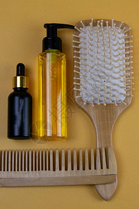 假发的化妆品包括焦糖阿甘或椰子油橙色背景的油瓶和梳图片