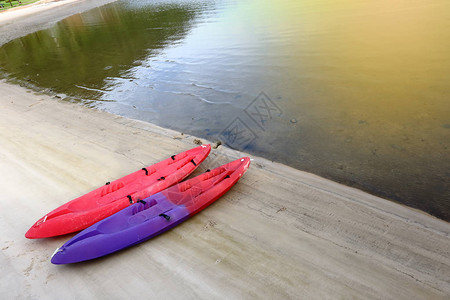 两艘红色和紫色的Kayak独木舟小船在沙滩海洋上概念号商业图片