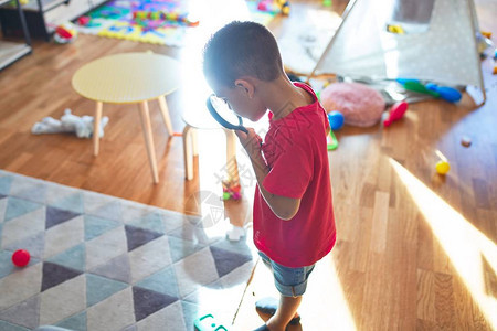 可爱的幼儿在幼儿园的许多玩具周围使用放大镜玩耍图片