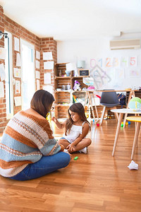 漂亮的老师和幼儿在幼儿园的许多玩具周图片