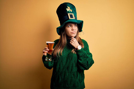穿着绿色帽子的年轻美女在圣徒节上喝杯啤酒抚摸痛苦的颈部喉咙痛得要感冒图片