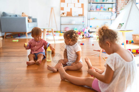 坐在地板上坐着可爱的幼儿童在幼儿园玩图片