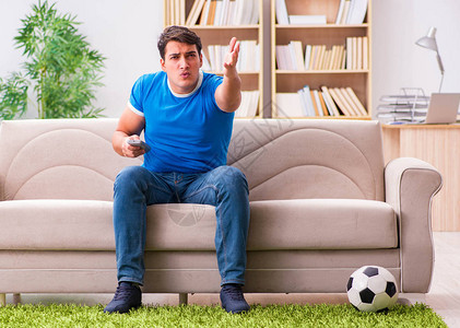 坐在沙发上在家看足球的人图片