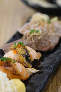 各种寿司装在黑盘子上一个人吃顿美味图片