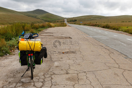 旅游自行车站在蒙古沥青路附近图片