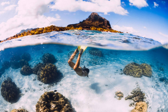 女孩自由潜水员在透明的海洋中用黄色的鳍在沙海上潜水在毛里求斯自图片