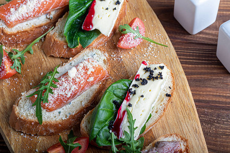 含红鱼的三明治苏维特牛肉和软奶酪涂满了微绿色青菜和番茄片在木质蛋白盘图片