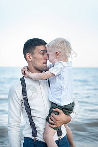 年轻父亲手牵着孩子去海边小孩拥抱爸图片
