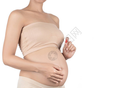 将孕妇的皮肤和手上的维他命药片隔离图片