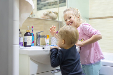 两个可爱的金发白人兄弟姐妹早上在家里的浴室里用牙刷洗脸和刷牙小孩子兄弟姐妹每天做higyene保健图片