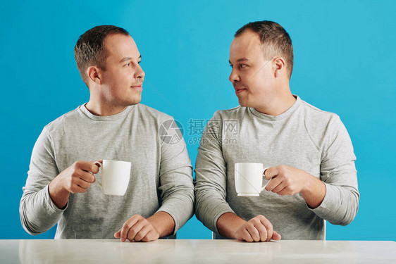 坐在桌边的年轻成年男双胞兄弟图片
