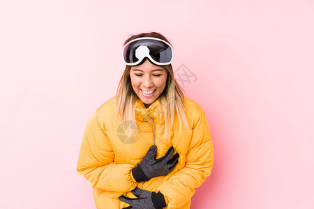 穿着粉红背景的滑雪衣的年轻高加索妇女笑得开心图片