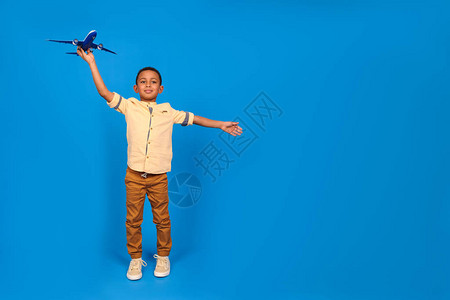 穿着棕色裤子和浅色衬衫的快乐男孩非洲裔美国人玩具飞机图片