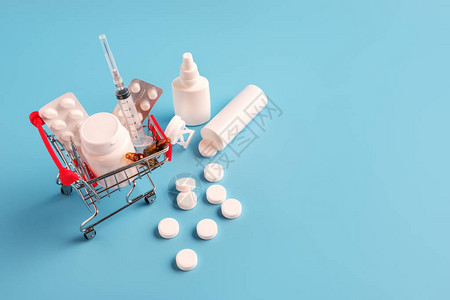 装有药丸和散片的购物车蓝色背景的迷你篮子里的各种药丸药物喷雾剂注射器药房购物概念图片