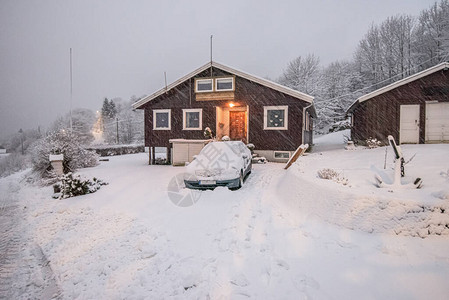 一座棕色房子的雪车道在冬天图片