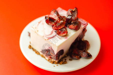 日本芝士蛋糕樱桃酱和新鲜樱桃在陶瓷板盘和红背景图片