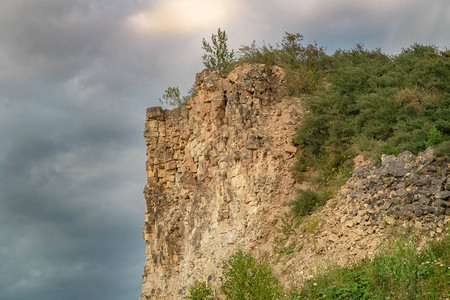 东崖绝壁在戏剧多云天空背景下开采后的高悬崖开发石灰岩山丘形成独特的建筑石灰采场绝壁风光风险背景