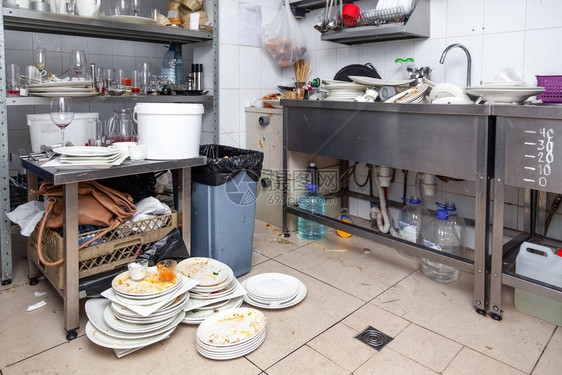 在金属水槽书架地板垃圾中专业餐厅厨房的脏盘子陶器许多玻璃杯剩饭图片