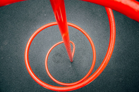操场上的螺旋是红色的儿童滑梯红色金属管结构扭曲成螺旋状带有红色条背景图片