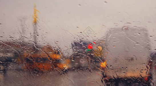 通过汽车挡风玻璃上的雨滴看到城市道路图片