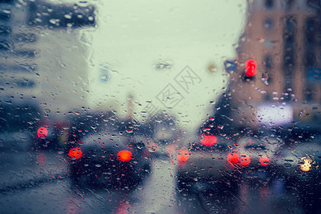 通过汽车挡风玻璃上的雨滴看到城市道路高清图片