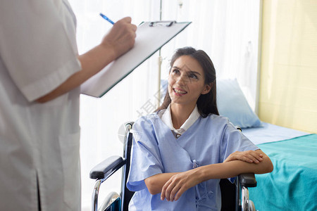 坐在轮椅上的医生和病人妇女在医院病房讨论图片
