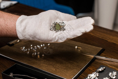 珠宝估价师在珠宝附近和桌子上拿着戒指图片