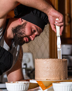 男面包师在新鲜烘烤生日蛋糕上散图片