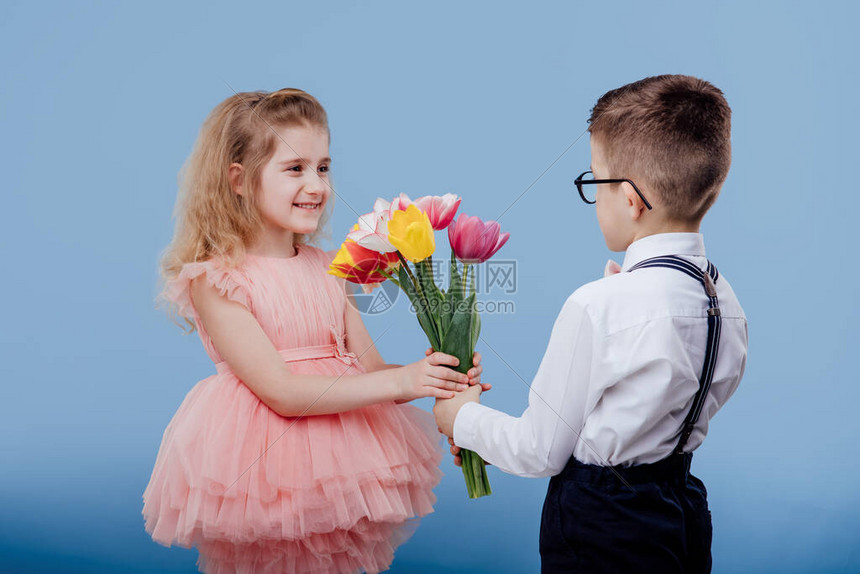 小男孩向一个穿粉红裙子的小女孩伸出鲜花图片