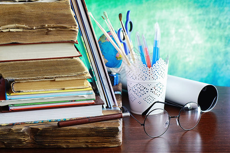 一叠教科书和桌上的一本带眼镜和电脑的书图片