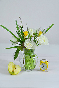 与一束春天的花朵和黄色闹钟的玻璃vaza束与柳絮和白玫瑰的褪色柳枝图片