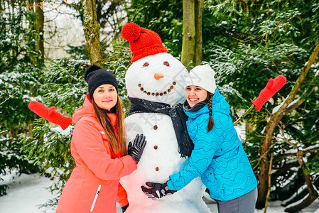 2名妇女在雪人附近摆姿图片