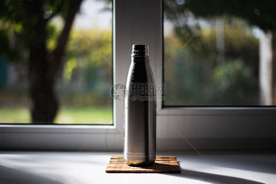 窗户背景上的钢制热水瓶图片