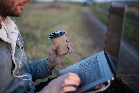 穿着笔记本电脑坐在腿上和手头咖啡图片