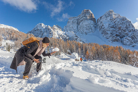 手里拿着雪球的金发女人用手机拍下令人敬畏的雪景图片