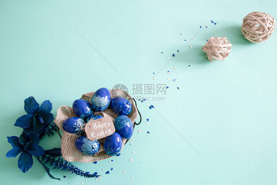 创造复活节布局由五颜六色的鸡蛋和蓝色背景的花朵制成圆形花圈平躺概念复活图片