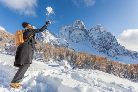 金发女子在意大利多洛米蒂山的佩尔莫山美丽的雪景前扔雪球图片