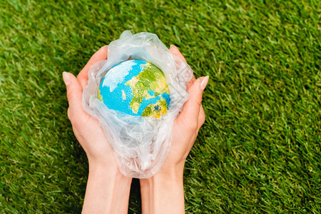以绿色全球变暖概念为女手中的塑料袋与全球塑料图片