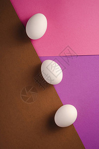 紫色粉红色和棕色的对角线排上的三个白蛋图片