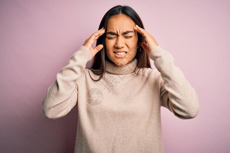 年轻漂亮的亚洲女人穿着粉红色背景的休闲高领毛衣图片