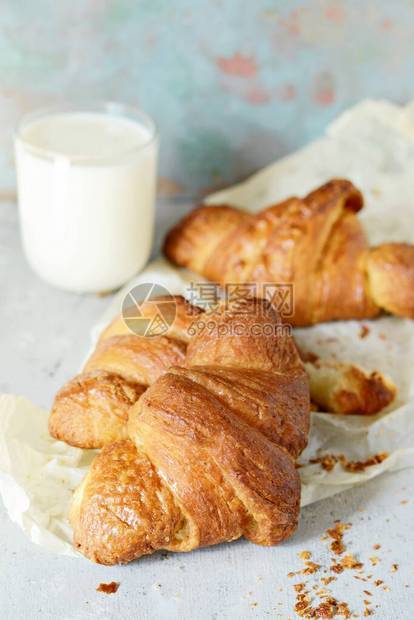 新鲜的法式羊角面包配一杯热牛奶和蜂蜜作为早餐背景上的自制法国羊角面包红润的外壳和新鲜出炉的香草味图片