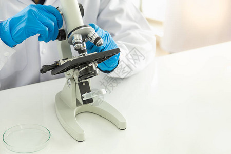 科学和医疗保健概念男医生科学家在白桌工作实验室中使用显微镜图片