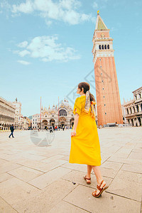 穿着黄色美容服和草袋走在威尼斯圣马可广场上的女人暑图片