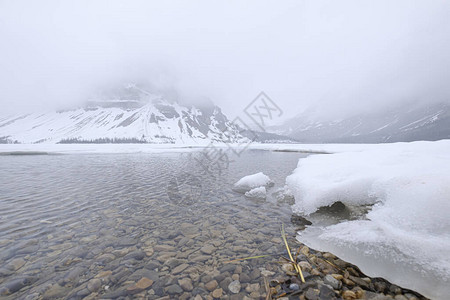 一个宁静的湖景环绕着雪覆盖的山丘贾图片