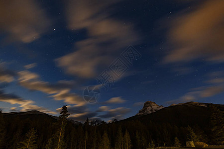 黑暗的山峰其背景是夜空有星和云彩图片