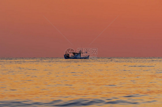 海上的红色日落渔夫船的剪影图片